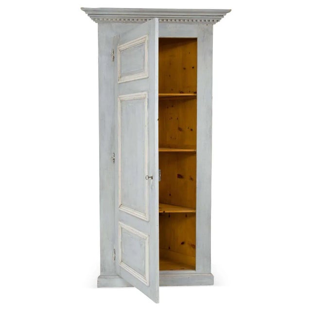 A single door painted French corner cabinet in the Louis XVI style. Made out of pine wood painted with light gray/blue and...