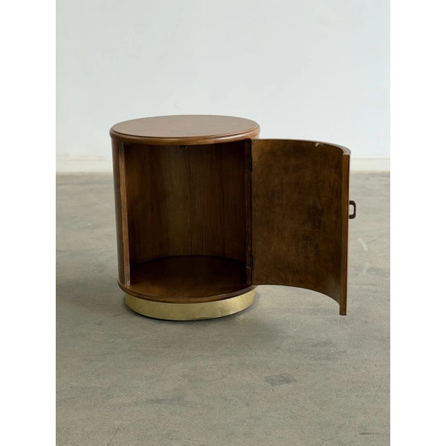 W18 H23 This vintage drum nightstand features rich burl wood veneer finished in a honey color and sits on a brass plinth...