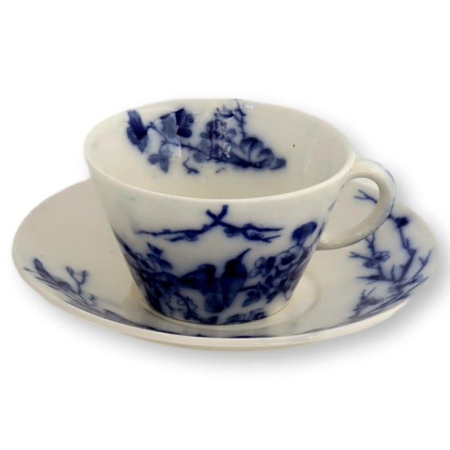 Flow blue cup and saucer with bluebird pattern. Made circa 1880. Cup, 4.5"W x 4"D x 2.25"H; saucer, 6.25"Dia x 1"H. Mark...