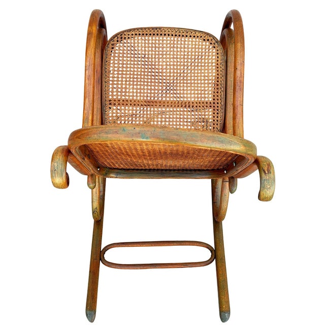 Turn of the century Vienna Secession bent oak No. 4 rocking chair by Thonet features an elegant, sculptural frame crafted...