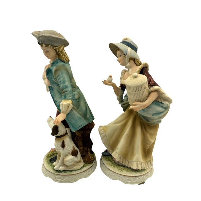 Classic Gallery by Napco Colonial Figurine Pair Dressed in period attire, the male figure has a dog and the female figure...