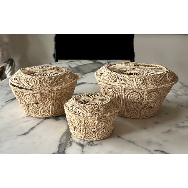 A charming vintage set of 3 handwoven nesting baskets crafted from natural rattan and reed that feature intricate spiral,...