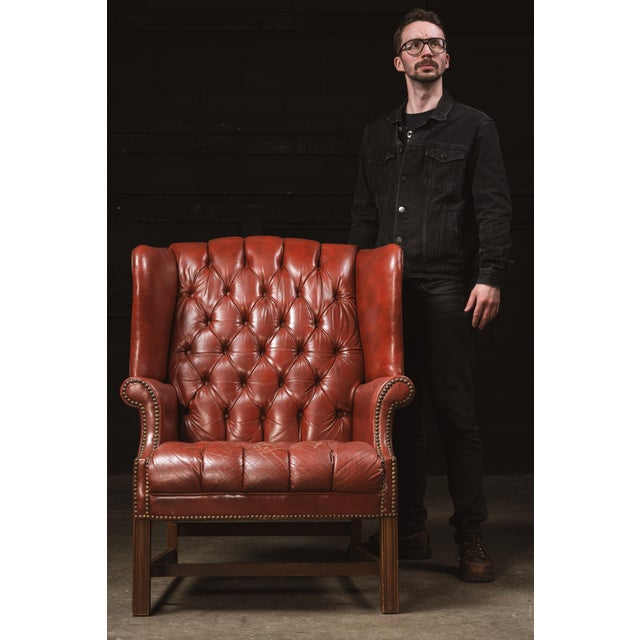 Vintage tufted leather armchair. This piece features a rich, red finish and sturdy wooden construction. The leather is...