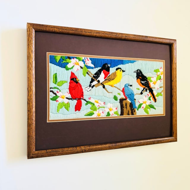 A vintage handmade needlepoint embroidery. Features the image of variety of colorful birds perched on branches. Well...