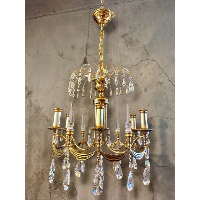Beautiful neoclassical Empire chandelier crafted in brass with richly cut prism crystals. The lamp features 6 elegant arms...