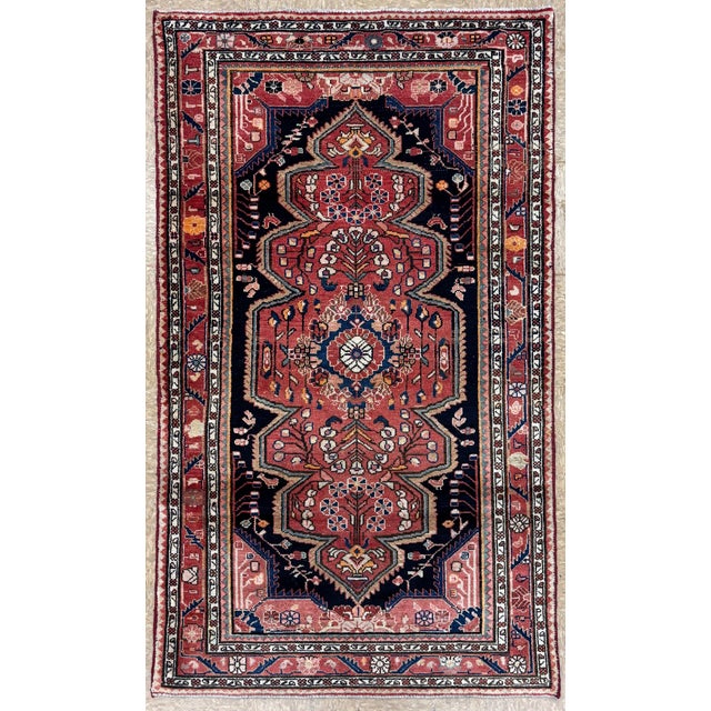 Hand-knotted village rug from the Hamadan region of western Iran, featuring a series of connected geometric medallions...