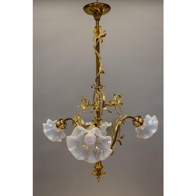 Elegant French Art Nouveau chandelier with sculptural bronze irises and opalescent glass shades. This refined French Art...