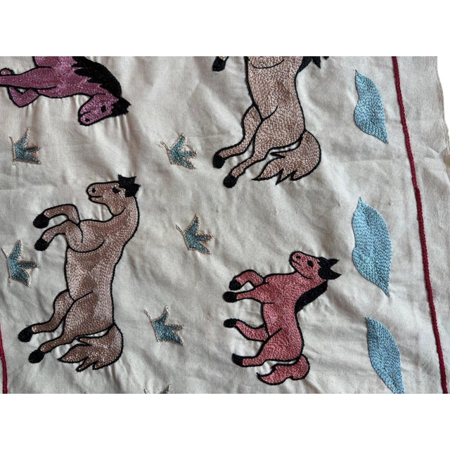 Hand-embroidered Suzani panel from Uzbekistan, worked in fine floss on a cream cotton ground. Twelve horses move across...