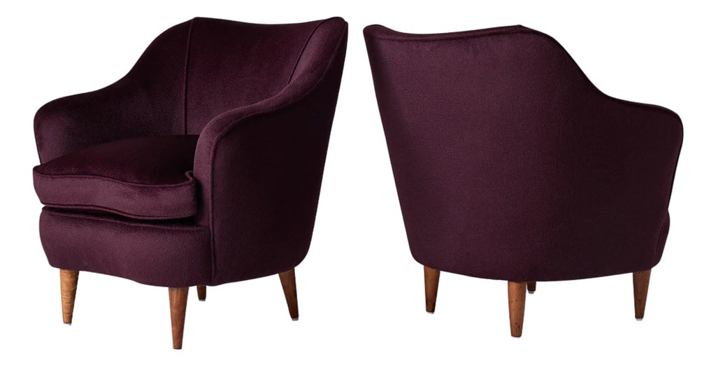 Two dark purple velvet lounge chairs side by side.