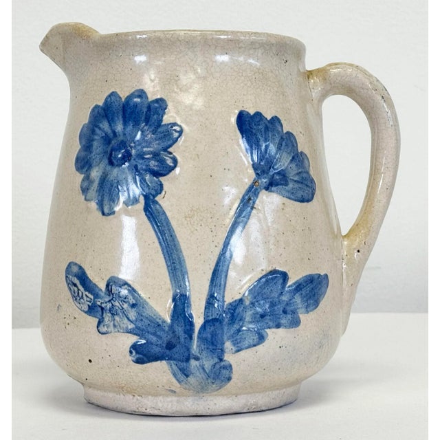 Antique McCoy Dandy line salt-glazed stoneware pitcher featuring embossed, hand-painted blue flower motif to both sides...