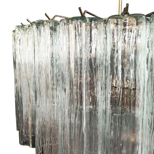 Made in Italy, this gorgeous round chandelier features a brass frame and three tiers of textured glass pendants, known as...