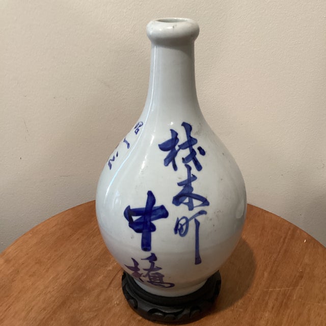 This Antique Japanese Tokkuri (Sake Long Neck Bottle) features intricate blue underglaze calligraphy, showcasing...