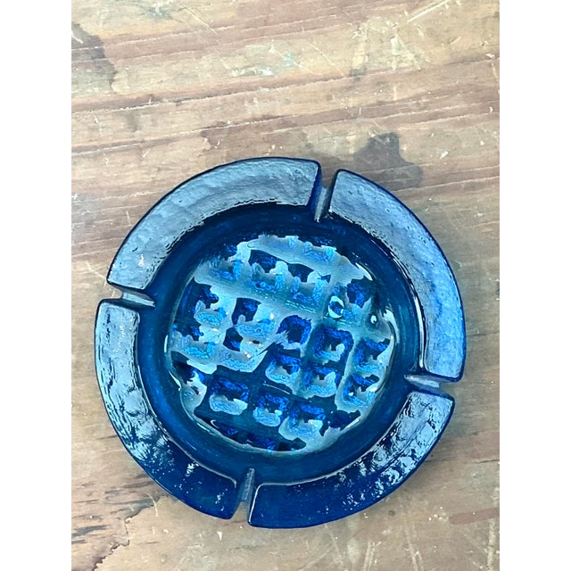 This substantial Mid-Century Modern ashtray is a vibrant example of 1960s art glass, featuring a deep cobalt blue hue that...