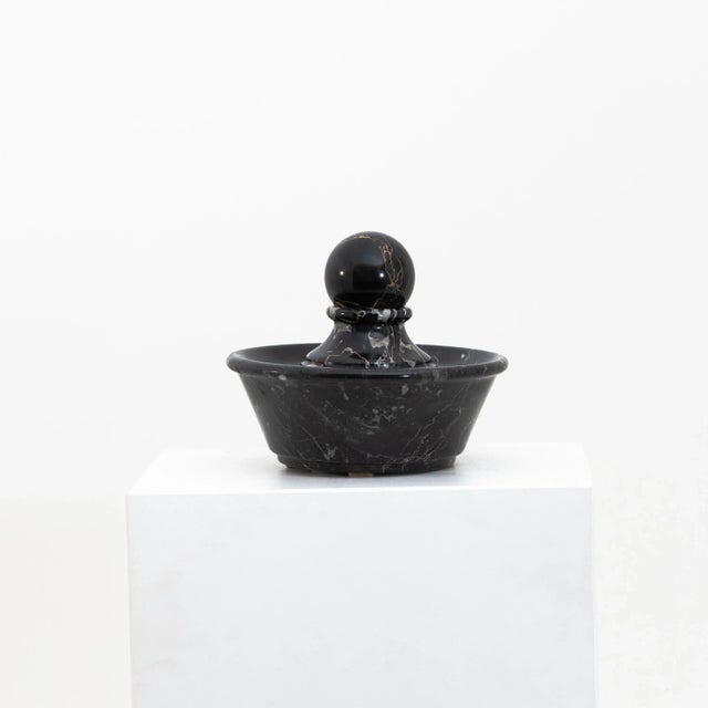 Small round table in black marble fountain with spherical cap.