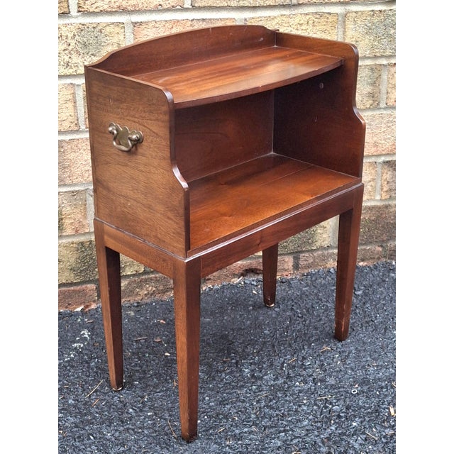 A mid 20th Century rich reddish brown mahogany bedside table nightstand. The design features two tiers: an open shelf area...