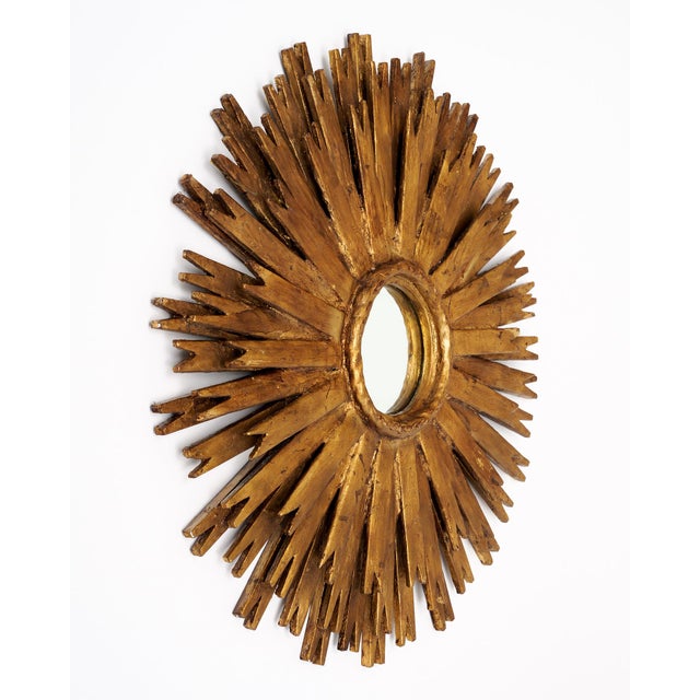 Sunburst mirror from Spain made of hand-applied gold-leafed wood. The rays emanate from a circular central mirror. The...