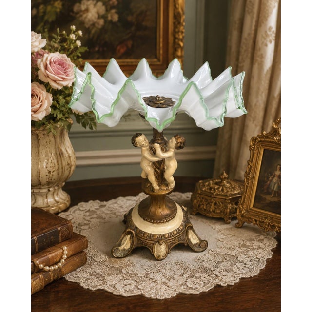 A striking vintage centerpiece featuring a dramatic Bohemian-style opal glass tazza mounted on an ornate cherub pedestal...