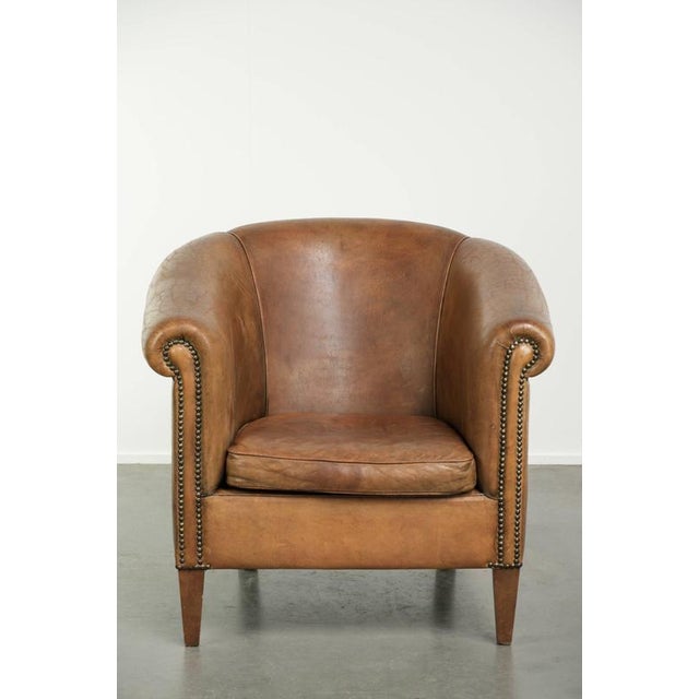 This lovely, large, and comfortable vintage sheepskin club armchair is crafted in a light cognac color and finished with...
