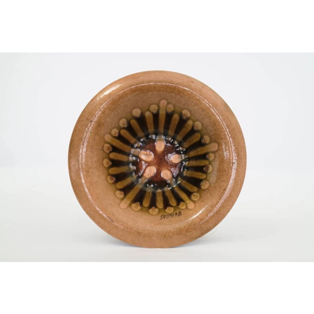 Enameled Metal, copper and brass tones.