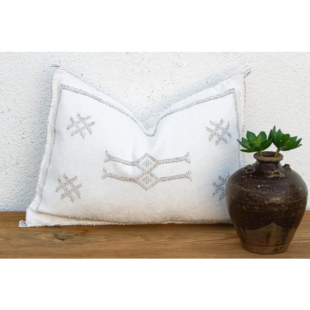 A crossed-star pair flanks a stacked geometric medallion on this handcrafted Moroccan cactus silk lumbar pillow, hand-...