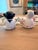 Two adorable figurines in the shape of a boy and girl. The boy is holding a pink koi fish and the girl is holding a yellow...