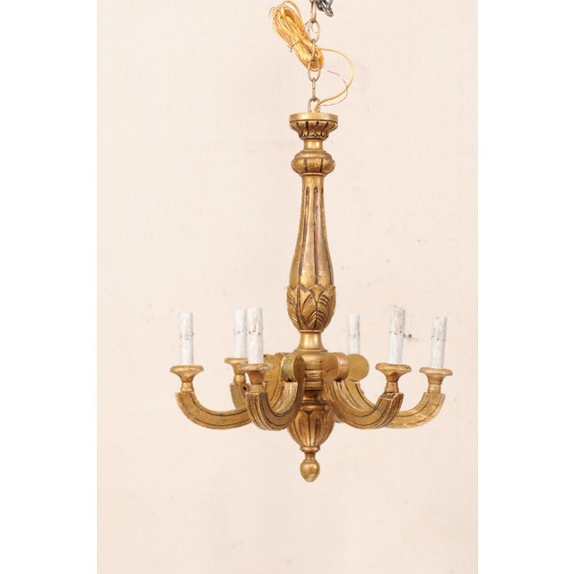 A French six-light carved and gilt wood chandelier from the mid 20th century. This vintage chandelier from France features...