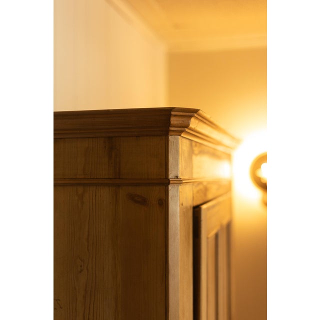This antique pine wardrobe showcases clean architectural lines, warm honey-toned pine, and beautifully paneled doors that...