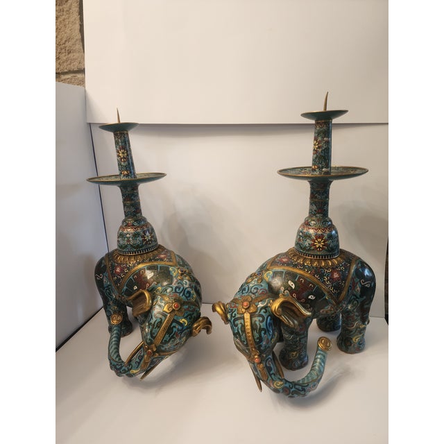 Each elephant stands on a fitted wood stand with slightly turned and lowered head and raised trunk. Detailed with...