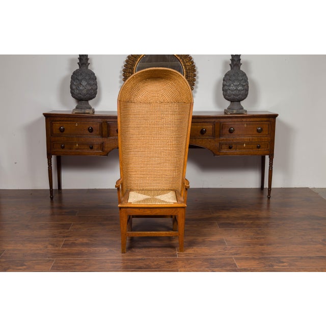 A Scottish Orkney Island canopy chair from the early 20th century with handwoven straw hooded back, rush seat, open arms,...