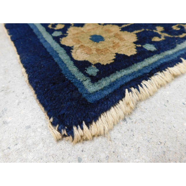 Central medallion on a plain field and floral motif on each corner, within floral decorated blue border. Circa 1925