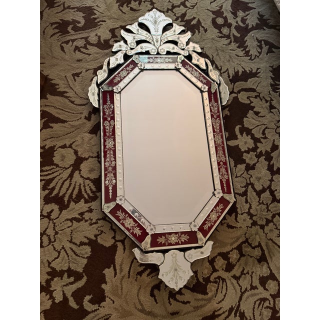 Ornate Venetian style wall mirror features a classic octagonal central pane surrounded by a striking ruby red glass...