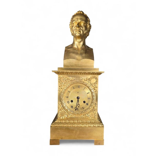 An elegant French Empire-style mantel clock crafted in gilded bronze, featuring a classic bust of a gentleman as its...