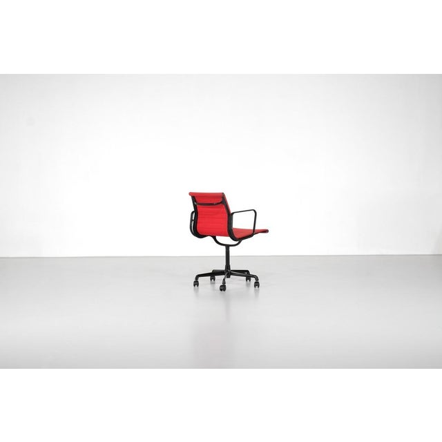 Swivel armchair, model "ea117", in red fabric with an aluminum frame on casters. Originally black, partially repainted,...