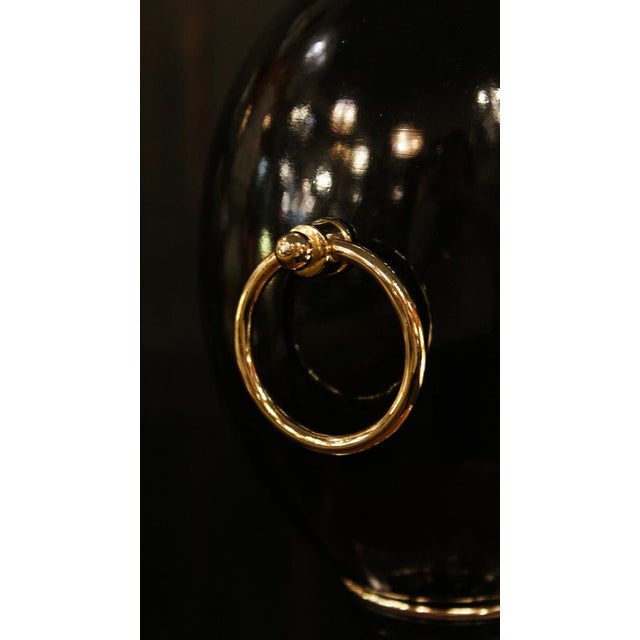 An elegant table lamp with a glossy black lacquered wooden body, accented with warm and sophisticated gold-plated brass...