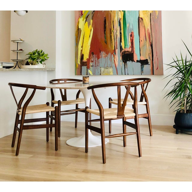 Walnut woven wishbone dinning chairs, set of four. Slight wear on two arms and one seat. Walnut Stain. Natural Seat Cord....