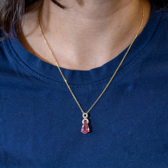 A 3.25-carat pink tourmaline pear sits at the centre of this solid 14K yellow gold pendant, framed by eighteen earth-mined...