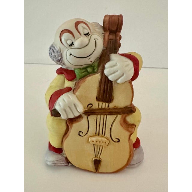 Vintage 1970s clown playing a cello bell. Bisque porcelain.