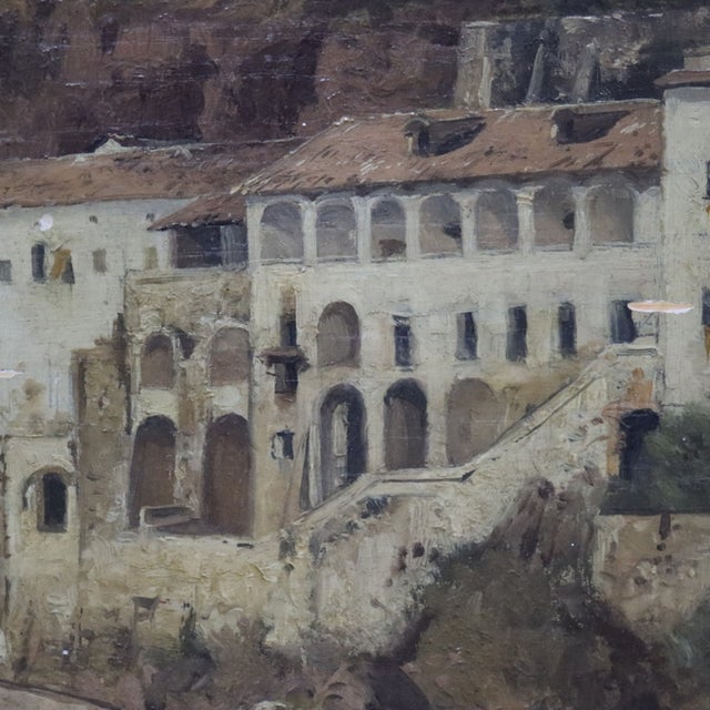 This antique German oil on board painting depicts a Mediterranean coastal landscape with a cliffside monastery. The...
