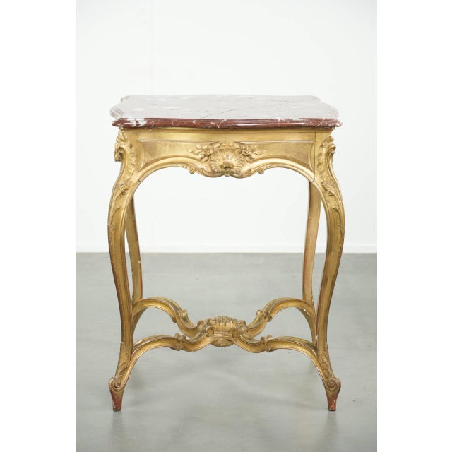 Offered by ByThijs is this antique French side table/center table from the 19th century with a gold-colored wooden frame...