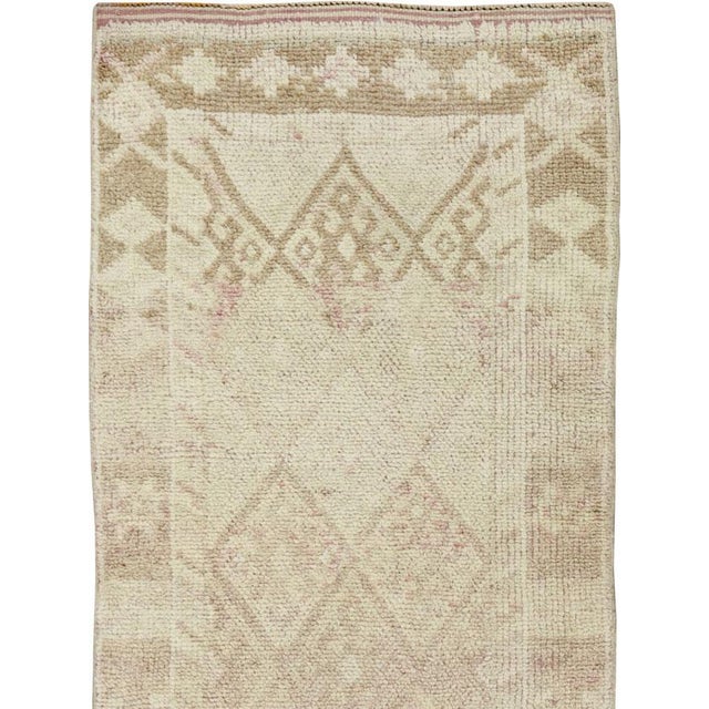 This mid-20th-century Turkish Anatolian runner presents a softly restrained composition in warm ivory, pale beige, and...