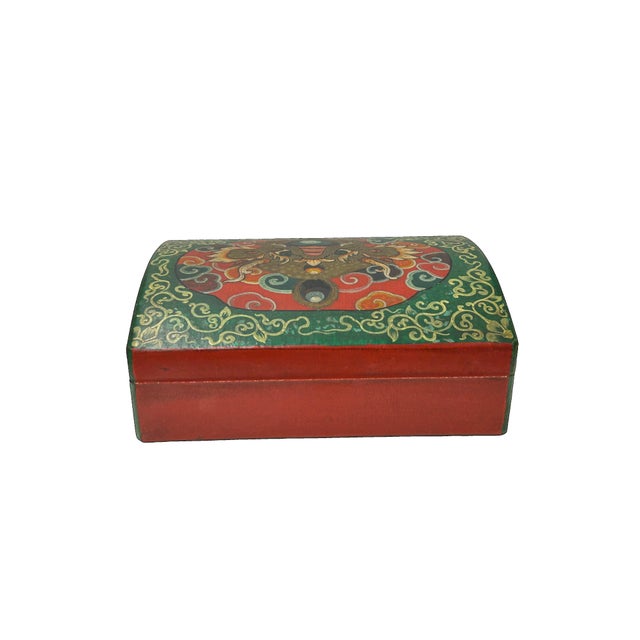 This ornate wooden box features traditional Tibetan-style hand-painted motifs, centered around a powerful Kirin mask on...