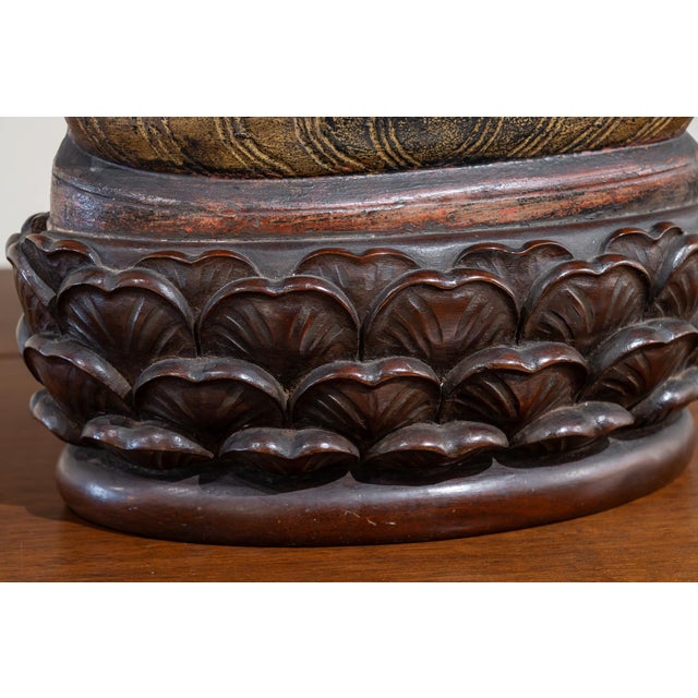 Sculpture of a seated Buddha carved in polychrome and gilded alabaster on a base of lotus petals made of wood. Buddha has...