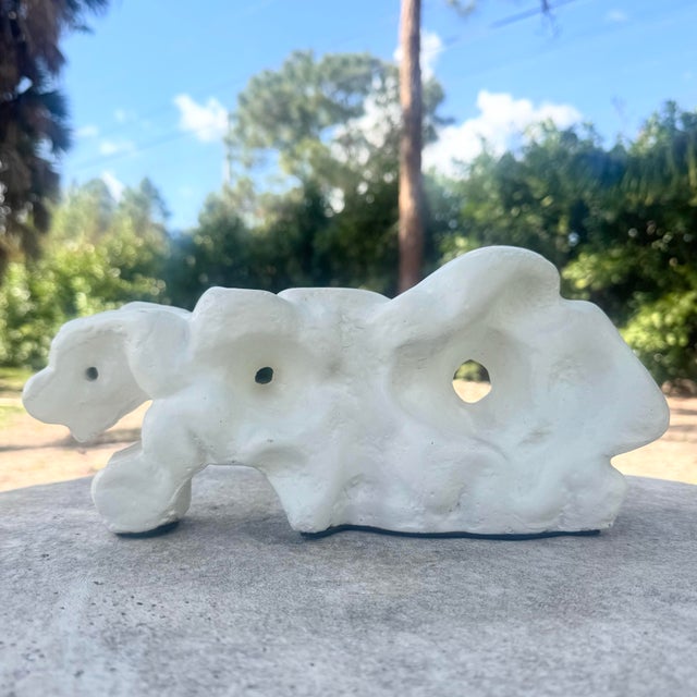 A striking minimalist abstract sculpture featuring an organic, free-form silhouette with heavily textured plaster...