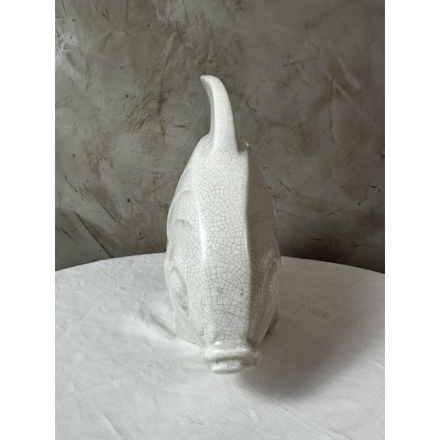 An elegant glazed earthenware sculpture with a crackle-like decoration depicting a stylized fish, typical of the Art Deco...