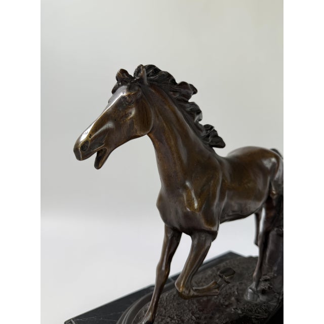 A beautifully modeled bronze sculpture capturing the power of a horse in motion, poised mid-stride with one foreleg lifted...