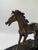 A beautifully modeled bronze sculpture capturing the power of a horse in motion, poised mid-stride with one foreleg lifted...