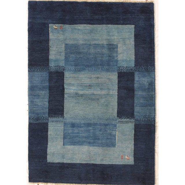 Vintage Hand-knotted Persian Lori Gabbeh rug featuring a tonal blue field structured with a bold geometric frame...