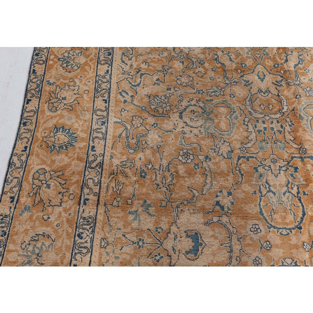 An early 20th century Persian Tabriz carpet, the golden yellow field with a delicate trellis overall of cloud bands,...