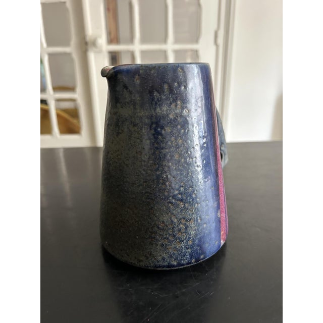 A glazed ceramic pitcher, circa 1950-1960, with a simple, modernist design. It features a graphic decoration composed of...