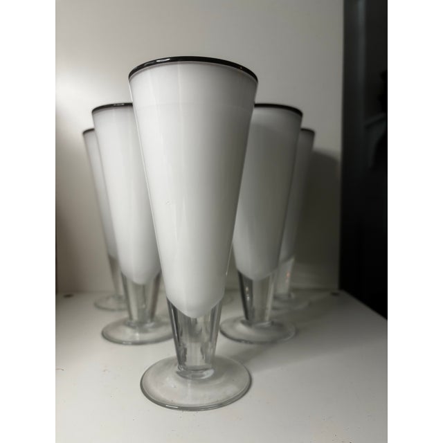 A striking set of six tall cased art glass highballs in opaque white with dramatic contrasting black rims. Each glass has...
